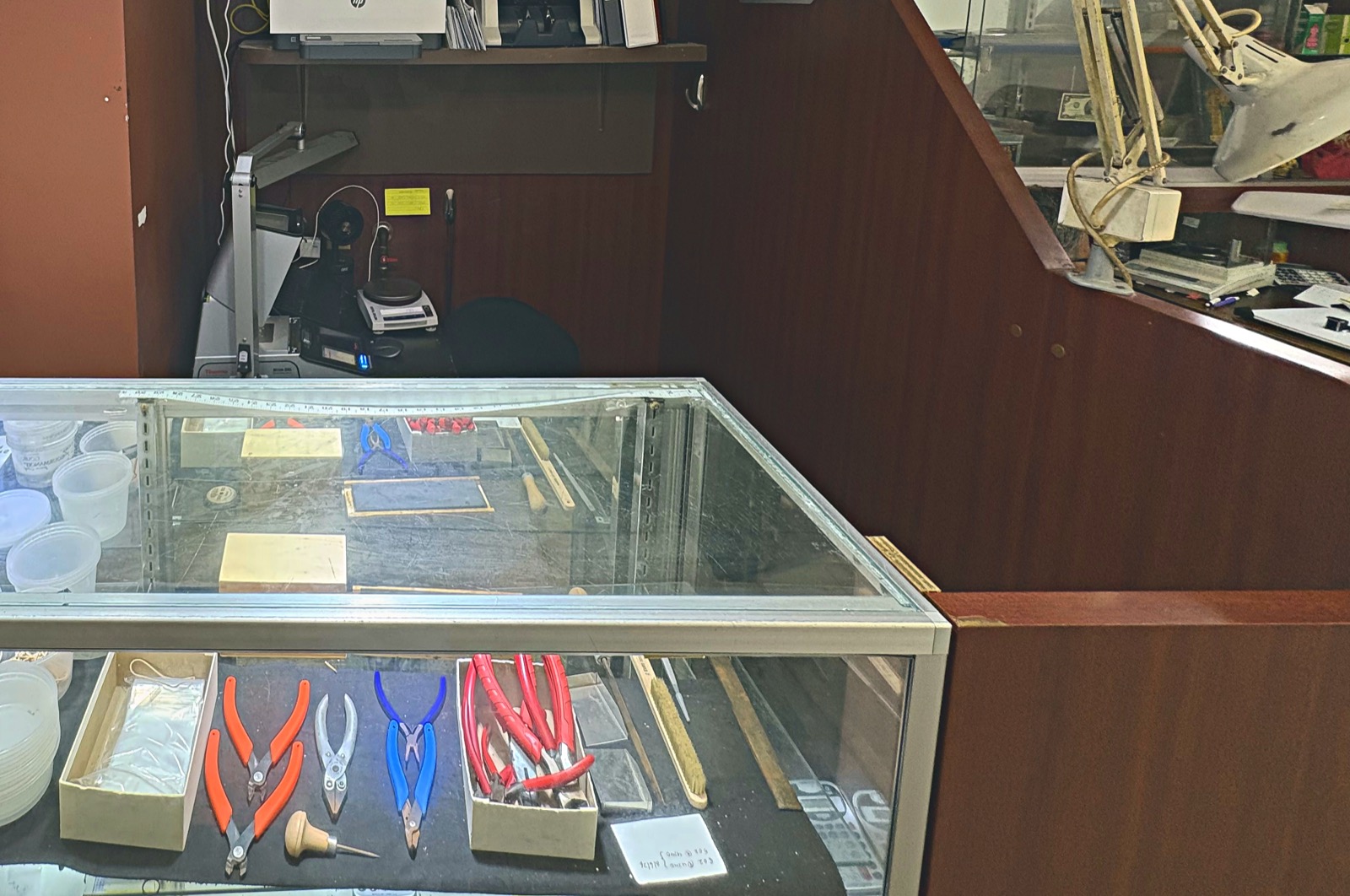The working counter at Booth 57: a precision scale and testing equipment behind a glass case of bench tools.